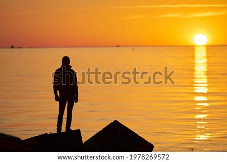 Woman or man standing on rock looking straight. Nature and beauty concept. Orange sundown. Girl silhouette at sunset Foto d'archivio © 