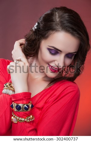 Girl brunette with purple eye shadows and golden bracelets on hand