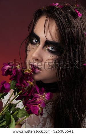 Girl with black makeup and wet hair and dried flowers