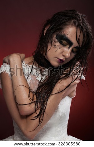 Girl in a wedding dress with black makeup and wet hair and dried flowers