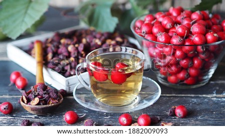 Bright berries of fresh hawthorn with dried berries and tea on a wooden background.Alternative folk medicine using hawthorn.