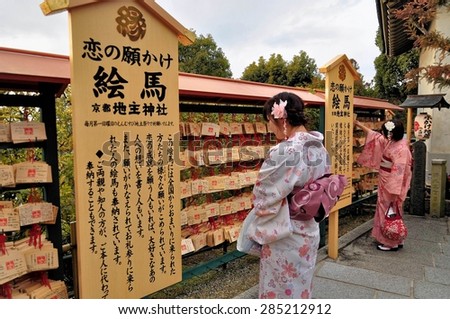 KYOTO, JAPAN - MARCH 1, 2014: Pretty Japanese young women in beautiful yukata  in front of wooden prayer plaques at Kiyomizu-dera, the temple of the Goddess of Mercy