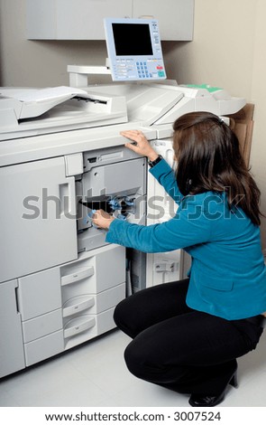 Young Woman Doing Routine Maintenance On An Office Photocopier