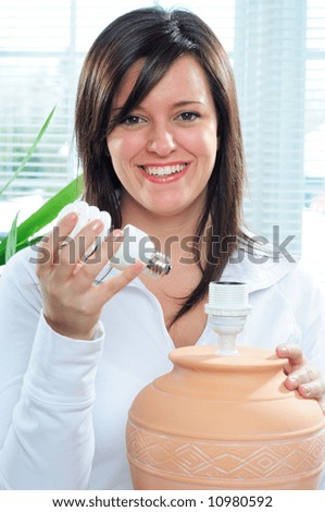 Young Woman Changing To An Energy Efficient Spiral Compact Fluorescent Lightbulb