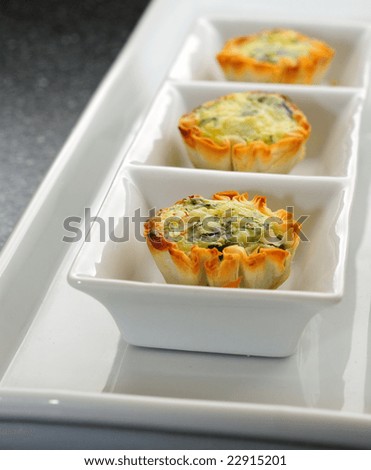 Small Individual Quiche Appetizers On A White Serving Dish