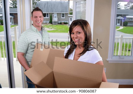 Young Couple Moving Into A New Home, Unpacking Cardboard Boxes