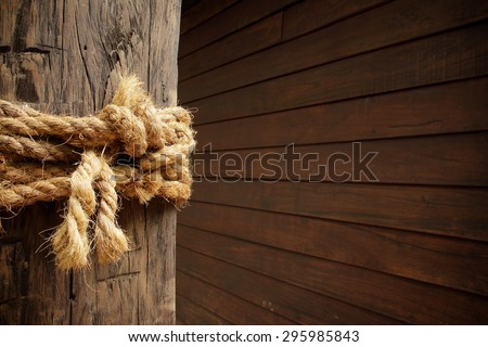 Rope wrapped around wooden post in old wooden wall