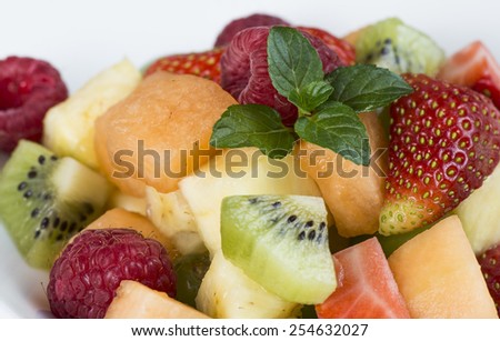 Gluten free fruit dish of kiwi, strawberries, cantaloupe, raspberries and pineapple.  All on a white plate.