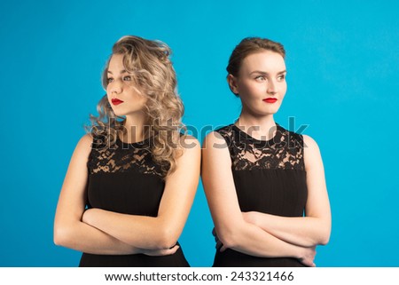 Two women in identical dresses are angry at each other/Two women in identical black dresses are angry at each other