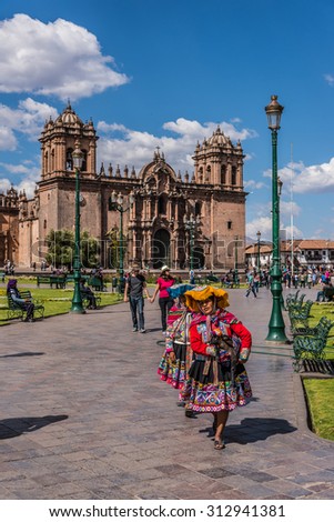 CUZCO, PERU - CIRCA 2015: Two unidentified women walk in the main square with de cathedral church at background circa 2015 in Cuzco, Peru.
