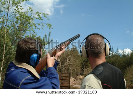 Man shooting clay pigeons being instructed
