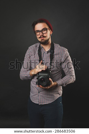 handsome guy with beard and mustache with vintage camera on dark background in studio