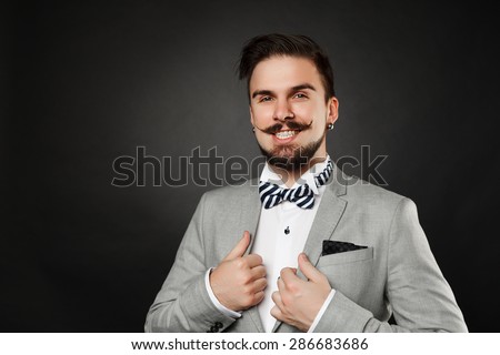 handsome guy with beard and mustache in suit on dark background in studio