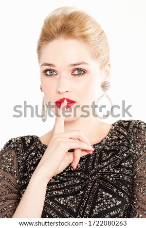 Glamorous young woman with finger on lips, portrait