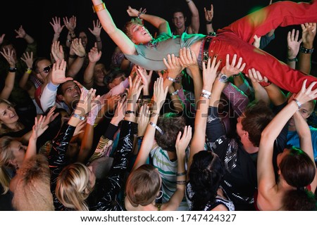 Performer body surfing across audience at concert