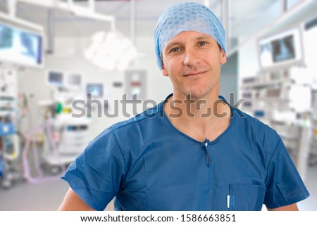 Portrait Of Male Surgeon Wearing Scrubs In Empty Operating Theater