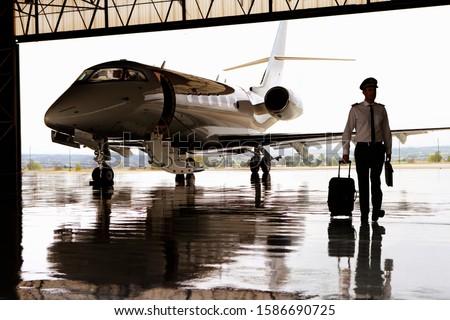 Silhouette of pilot walking away from private jet in hangar Foto stock © 