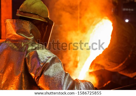 Worker In Protective Clothing Pouring Molten Metal In Foundry 商業照片 © 