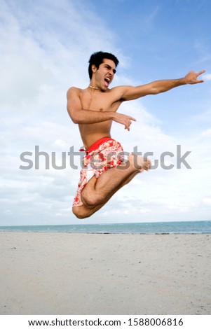 A man in shorts jumping on a beach
