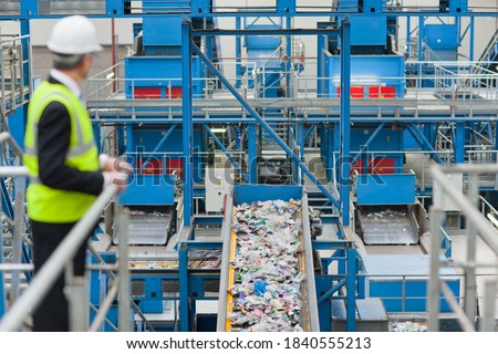 Businessman watching plastic on conveyor belt in recycling plant