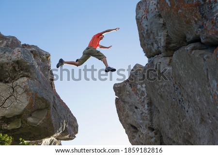 Imagen de un escalador rocoso macho saltando entre rocas.