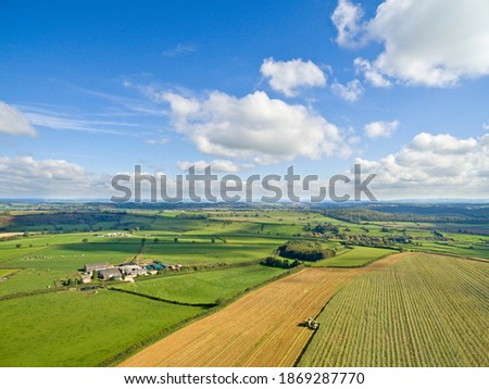 Wide scenic aerial view of green rolling landscape under the sunny blue sky with clouds