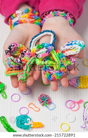 Child holding homemade rubber band bracelets.