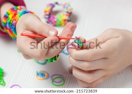Closeup of child hands making rubber band craft.