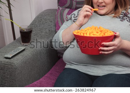 Overweight woman eating junk food in the coach.