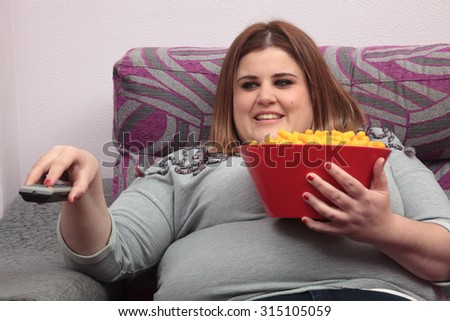 Woman zapping and eating junk food