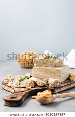 Pieces of sunflower and peanut halva and mint leaves on a cutting board on the table. Caloric oriental dessert. Vertical view Foto stock © 