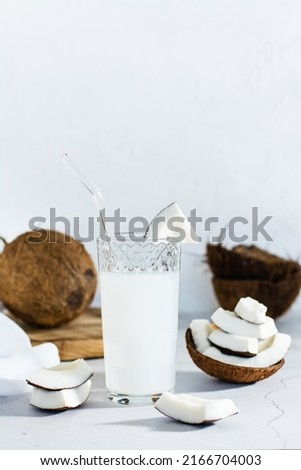 Coconut milk in a glass and pieces of tropical fruit on the table. Natural source of antioxidants, plant alternative. Vertical view Imagine de stoc © 