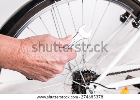 Woman hand repair bicycle whee with screw key - studio shoot