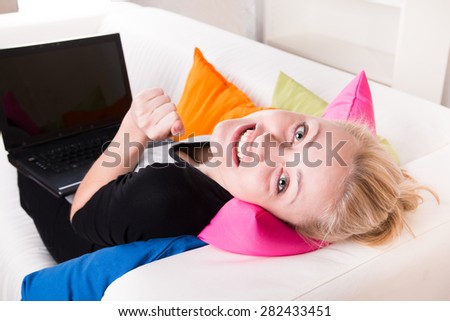 Girl with a laptop on belly and lying on the sofa at home