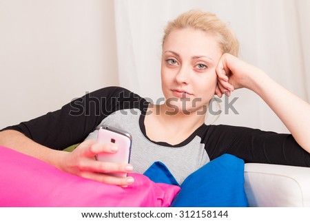 A girl waiting for a phone on the sofa at home