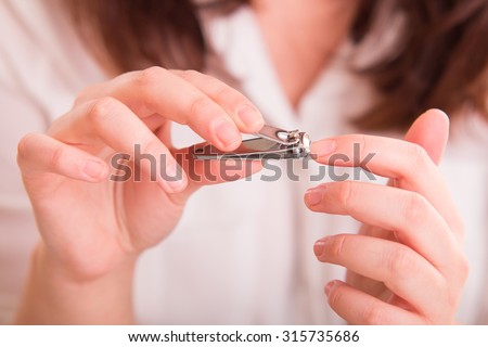 Woman cutting nails using nail clipper - close up