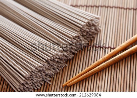 Raw soba noodles and chopsticks on bamboo napkin. Soba is a type of thin Japanese noodle made from buckwheat flour. Close-up.