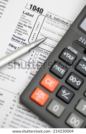 1040 Tax Form with ballpoint pen and calculator. Focus on pen. Closeup.