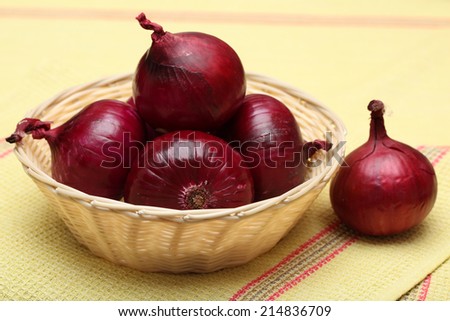 Red onions in the basket and red onion on tea towel.