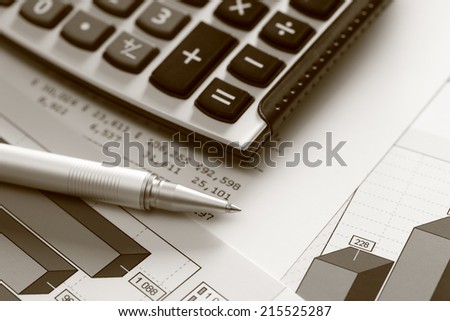 Financial statements. Business Graph. Ballpoint pen and calculator on a financial chart or Stock Market Data. Black and White (Sepia).