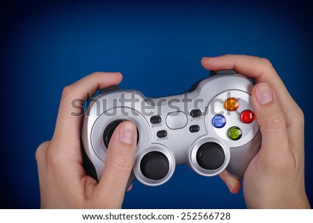Young woman plays video game using a game pad. Blue background. Vignette.