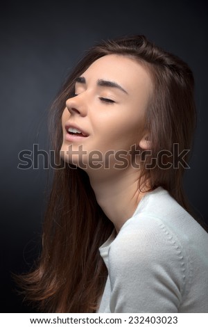 Young woman posing with closed eyes on a black background. Without makeup.
