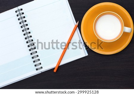 Open a blank white notebook, pencil and a glass of milk on a desk. The light nature morning.