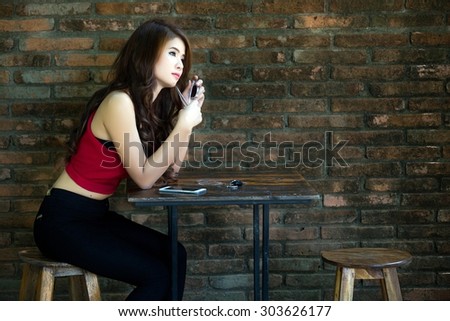 Beautiful asian woman relaxing alone at the table. The background is the old brick wall