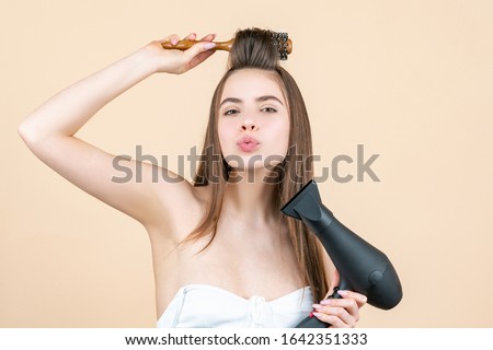 Blow dryer. Drying long brown hair with hair dryer and round brush. Hairdresser blow drying her hair. Beautiful girl using a hair dryer