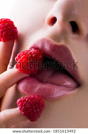 Sexy pink lips with raspberry. Womans enjoying. Female eating raspberry. Sensual enjoyment. Closeup female mouth tasting raspberry. Sweet enjoyment. Sexy and erotic concept