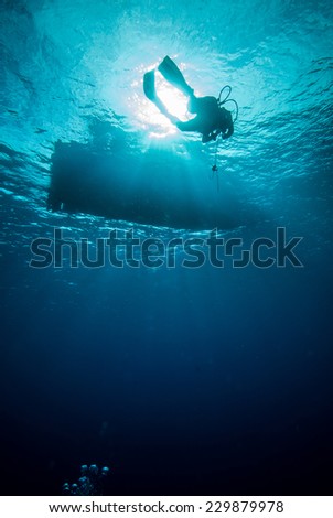 Underwater sunshine below the boat in Derawan, Kalimantan, Indonesia underwater photo. Diver swim heading to the boat.
