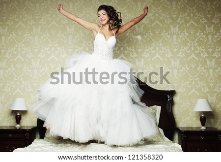 Young happy bride jump on bed.