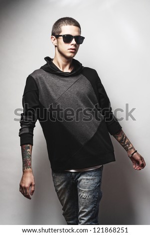 Portrait of young male fashion model with arm tattoo and sunglasses