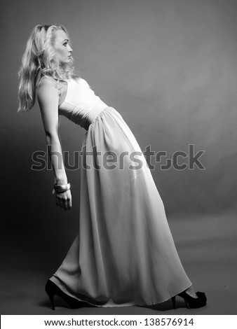 Luxury Fashion model, a beautiful woman posing in studio on gray background. Black and white photo.
